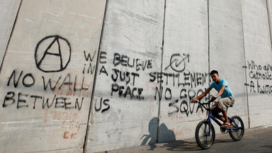 Ein arabischer Junge fährt im Osten Jerusalems auf einem Rad am Trennwall zwischen Israel und den palästinensischen Gebieten entlang.