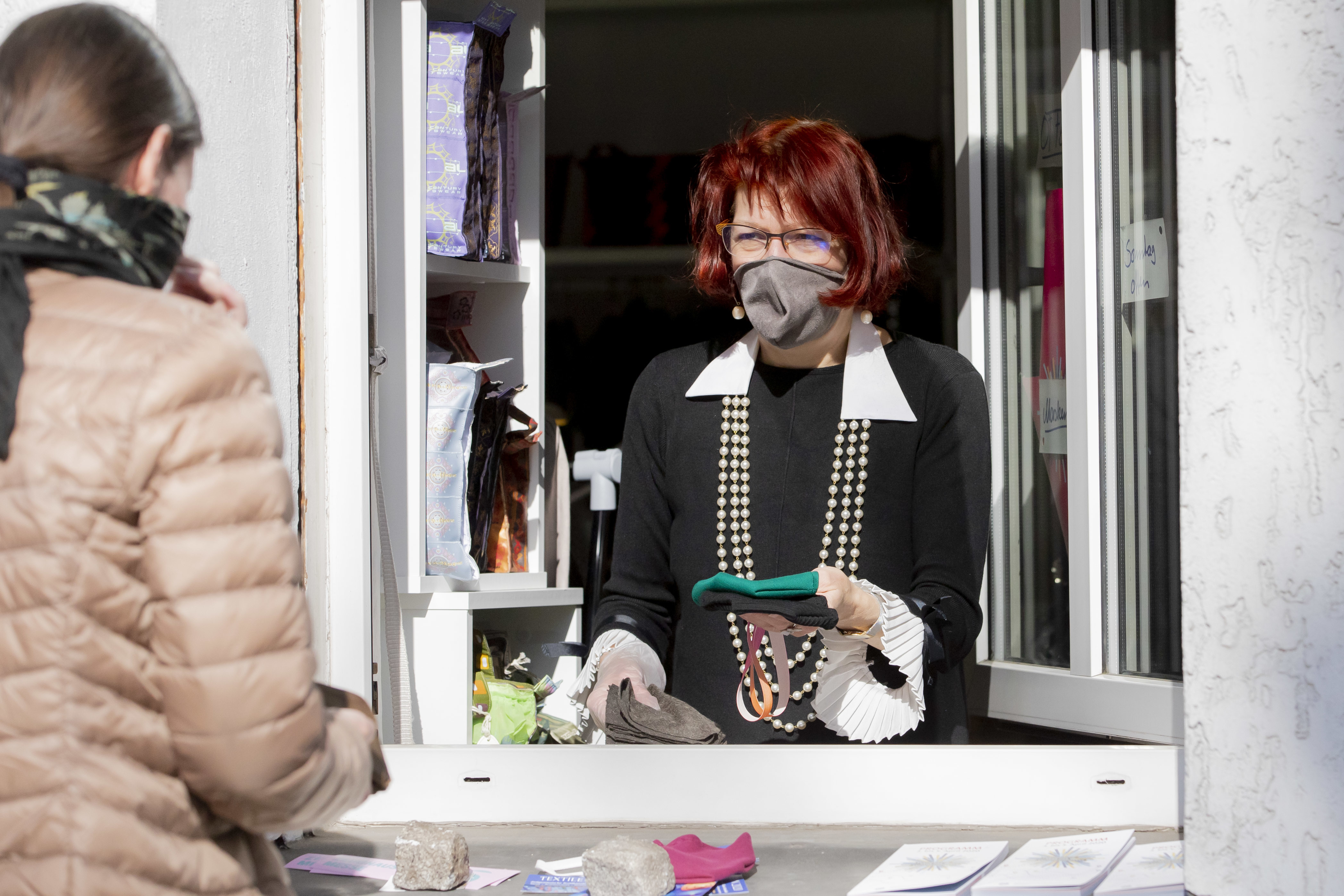 Diese Textilkünstlerin bleibt optimistisch und verkauft aus dem Fenster ihres Geschäfts in Berlin-Schöneberg Schutzmasken.