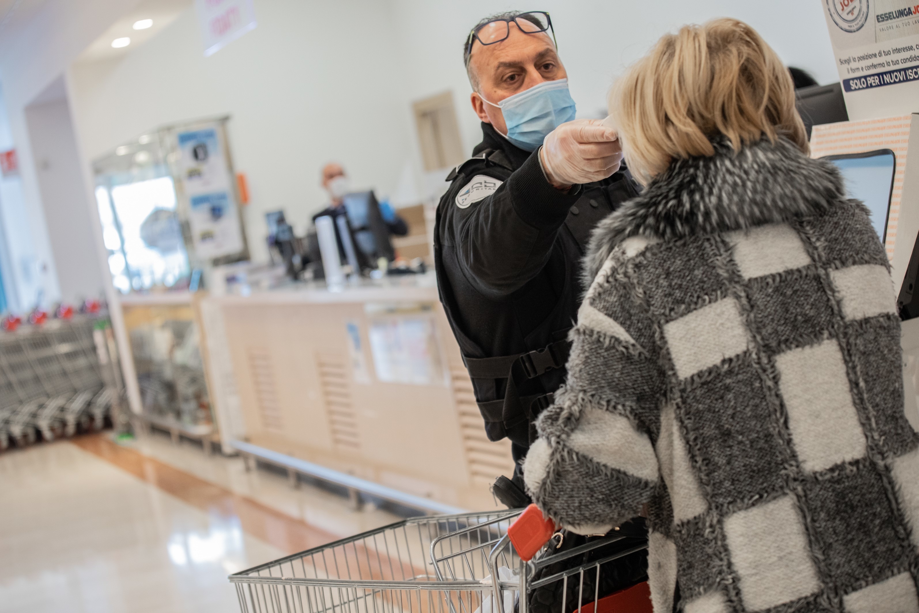 Eine Frau wird vor dem Betreten des Supermarktes auf Fieber kontrolliert.