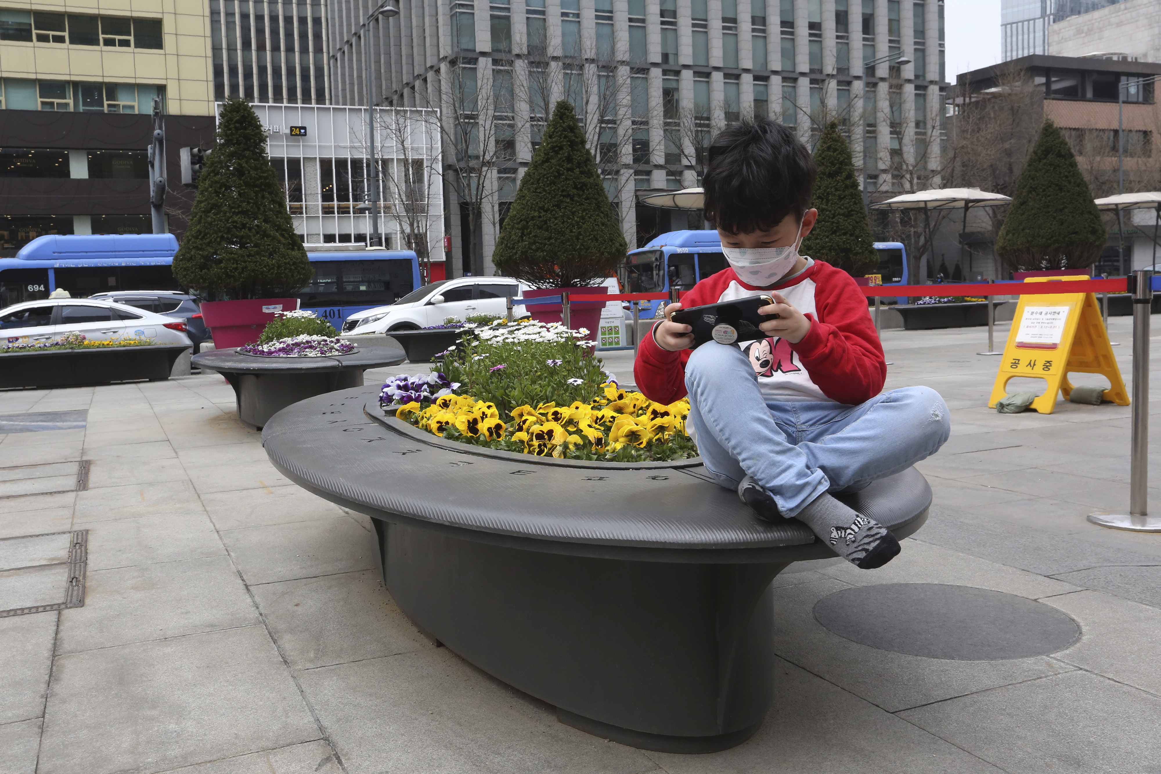 Ein kleiner Junge spielt mit seinem Smartphone in der Innenstadt von Seoul