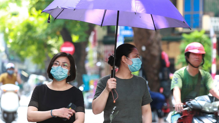Frauen mit Gesichtsmasken gehen in Hanoi auf die Straße