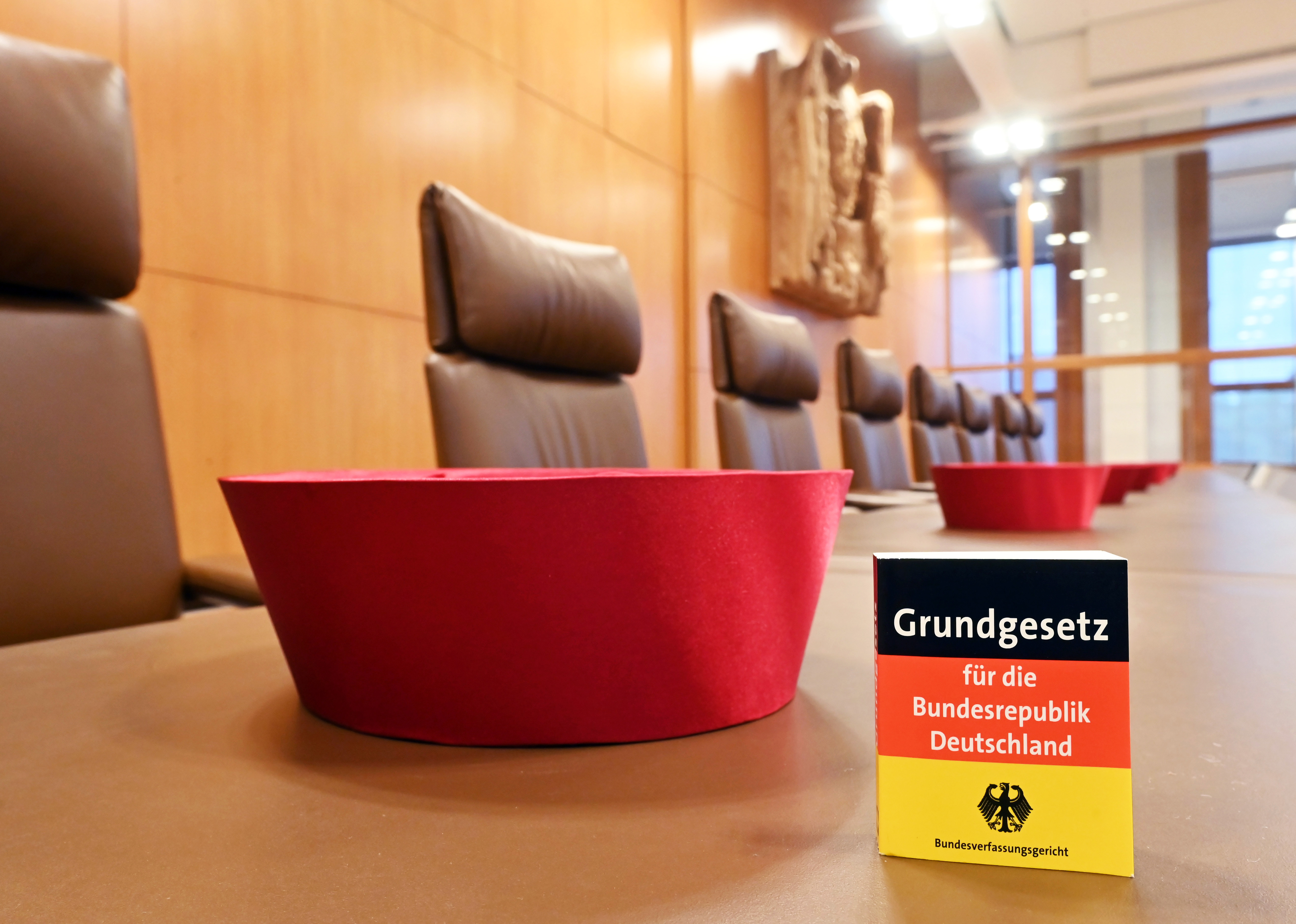 Auf der Richterbank im Sitzungssaal im Bundesverfassungsgericht liegen Barette der Bundesverfassungsrichter des ersten Senats. Dabei ist eine Miniaturausgabe des Grundgesetz für die Bundesrepublik Deutschland zu sehen. Im September 2021 feiert das Bundesverfassungsgericht seinen 70. Geburtstag. 