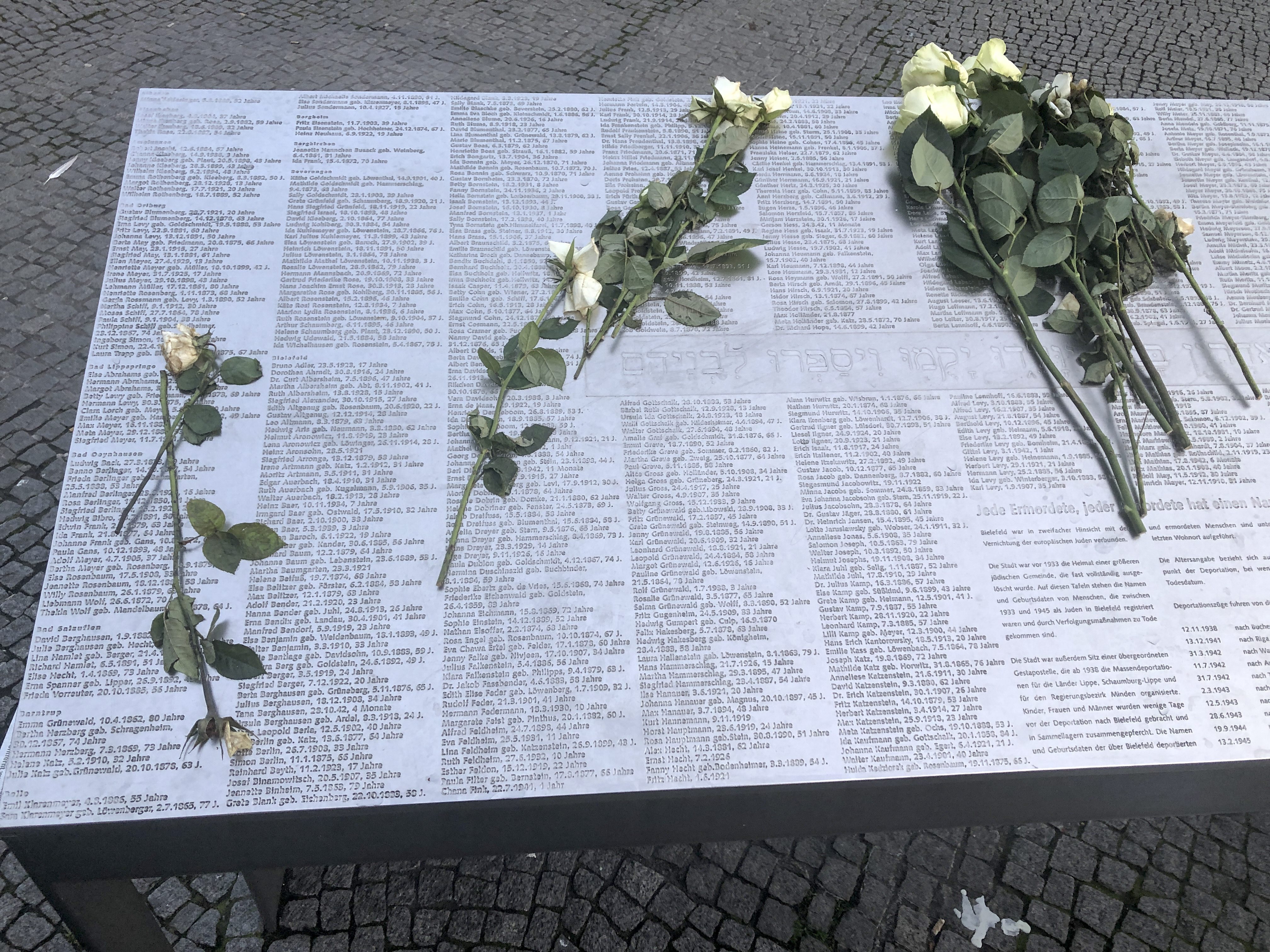 Weiße Rosen liegen zum Jahrestag der Reichspogromnacht auf der Gedenkplatte mit den Namen der im Dritten Reich aus Bielefeld deportierten Jüdinnen und Juden 