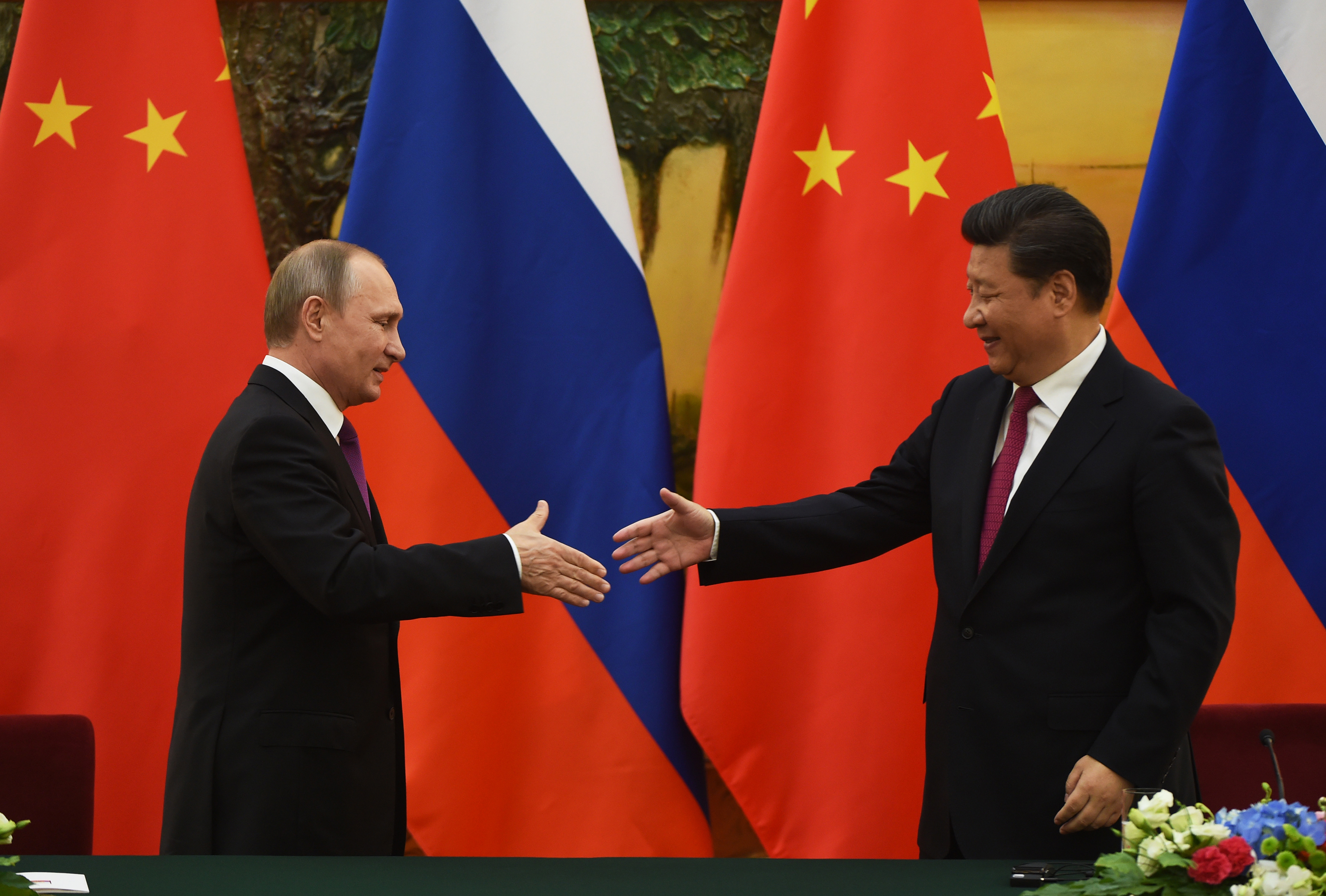 Russian President Vladimir Putin, left, shakes hands with Chinese President Xi Jinping