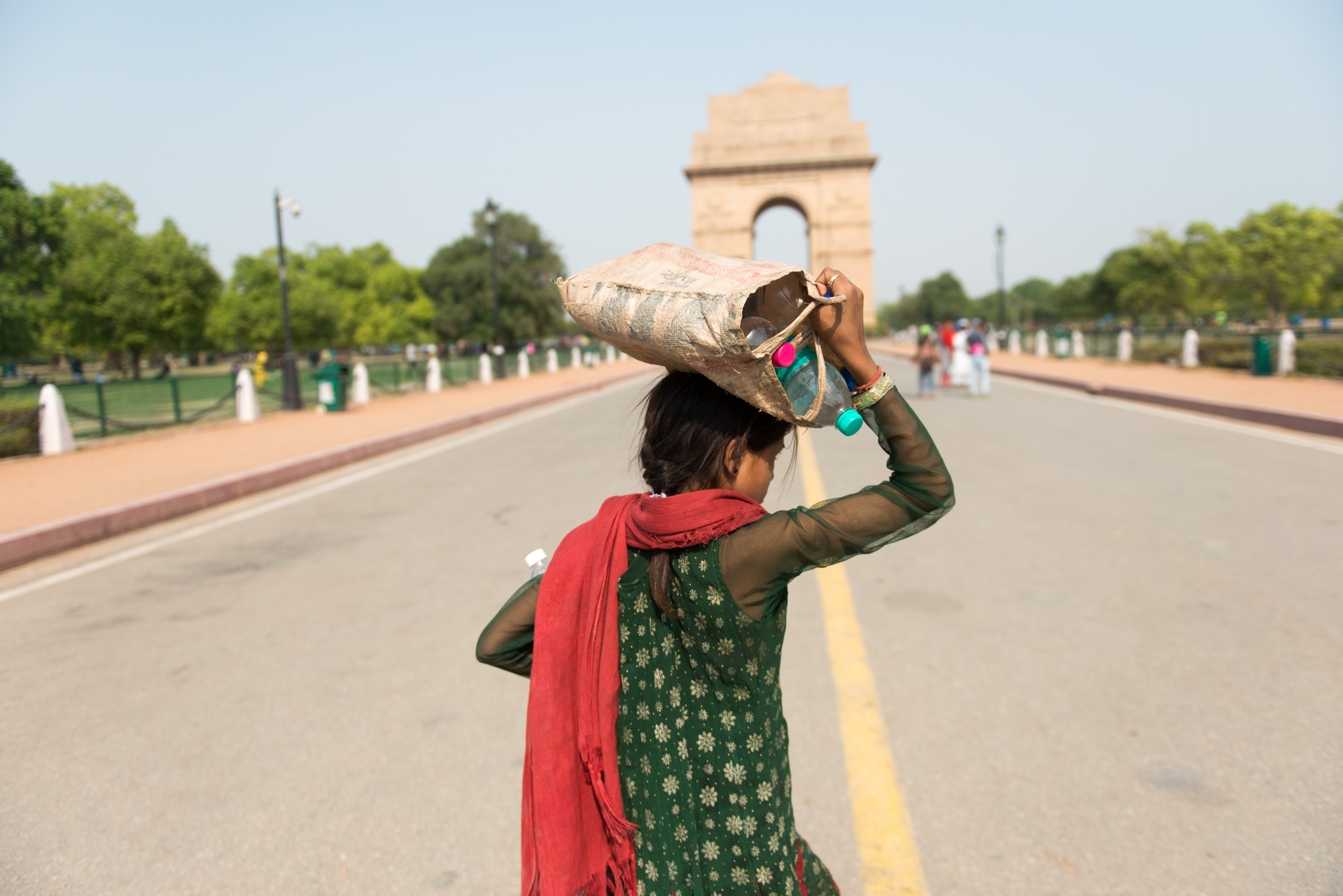 New Delhi, India, a girl carrying drinkable water bottles on her head during summer near India Gate