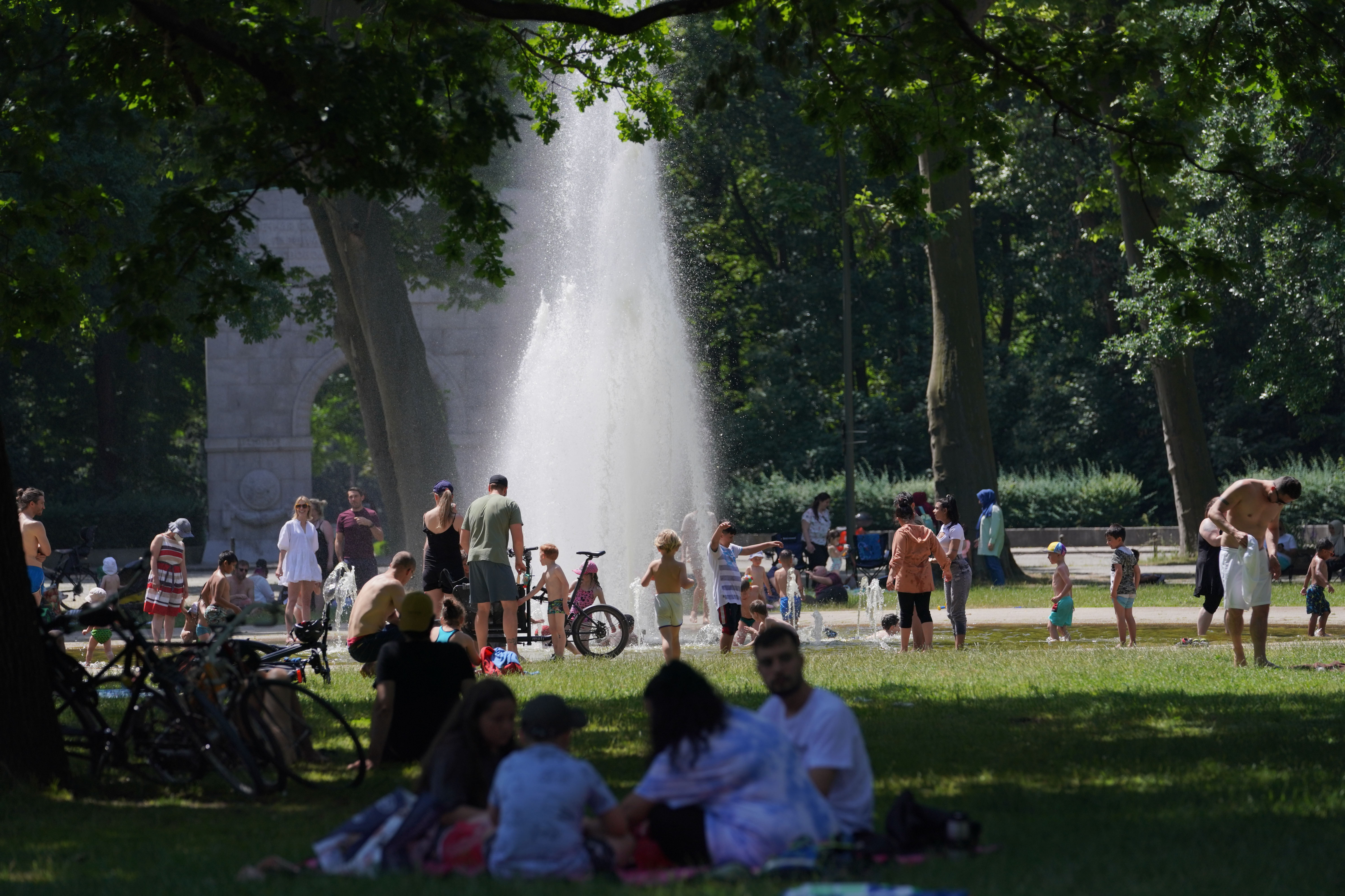 Zahlreiche Menschen suchen bei hochsommerlichen Temperaturen den kühlenden Springbrunnen im Treptower Park auf.