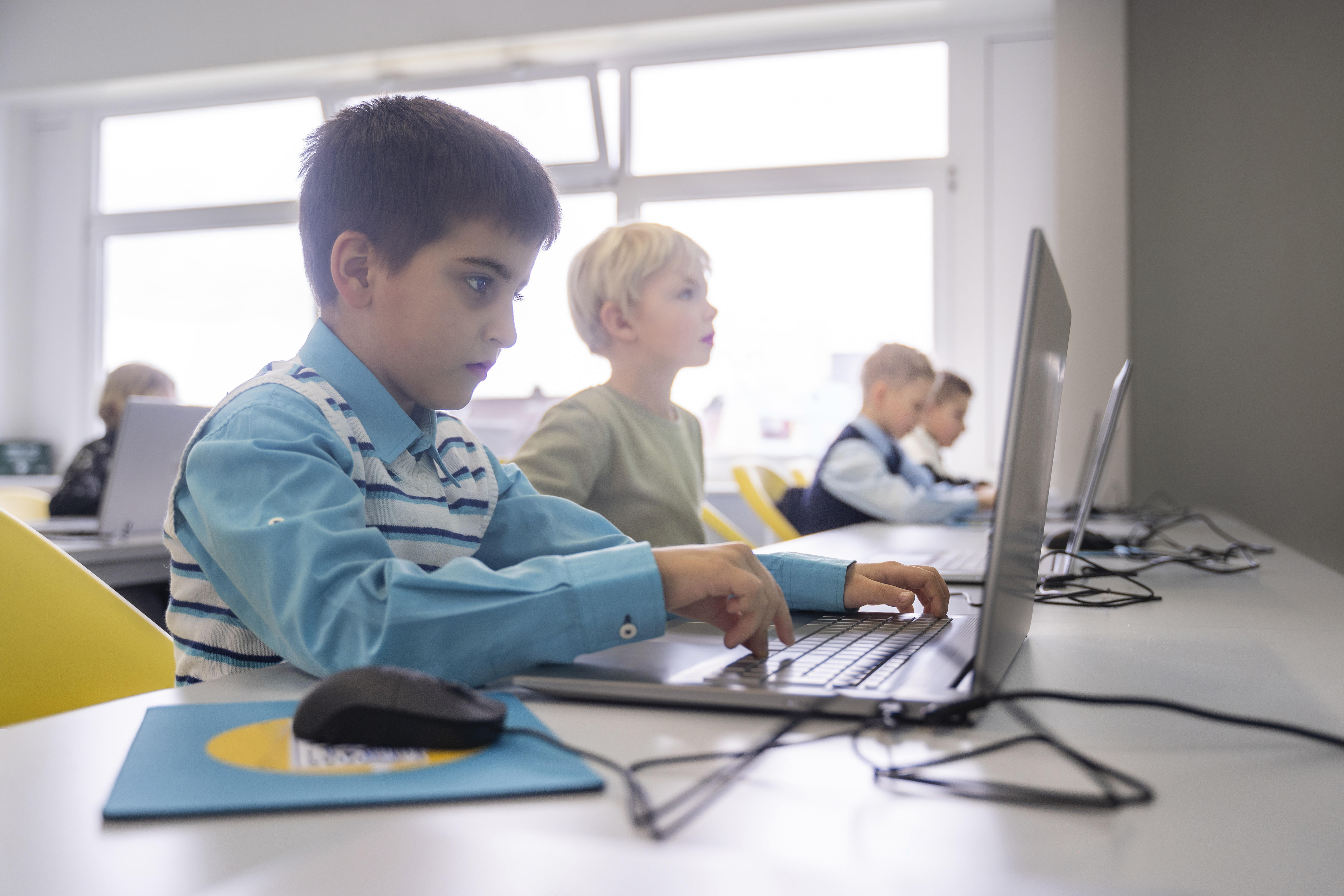 Junge beim E-Learning mit Laptop am Schreibtisch in der Schule