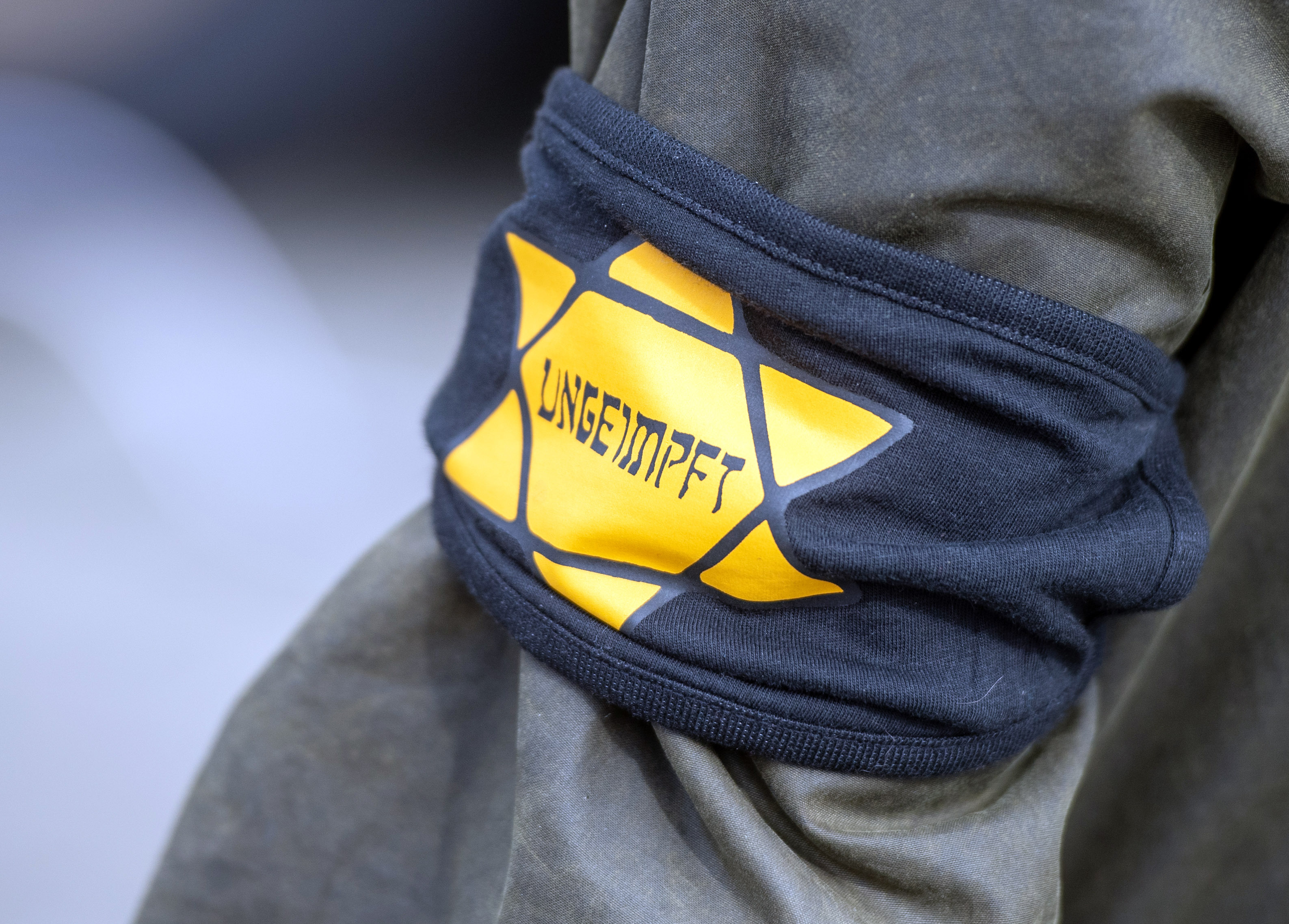 Bei einer Demonstration gegen die Einschränkungen durch die Pandemie-Maßnahmen der Bundesregierung am Brandenburger Tor trägt ein Teilnehmer eine Armbinde mit einem gelben Stern, der an einen Judenstern erinnern soll, mit der Aufschrift «Ungeimpft». 