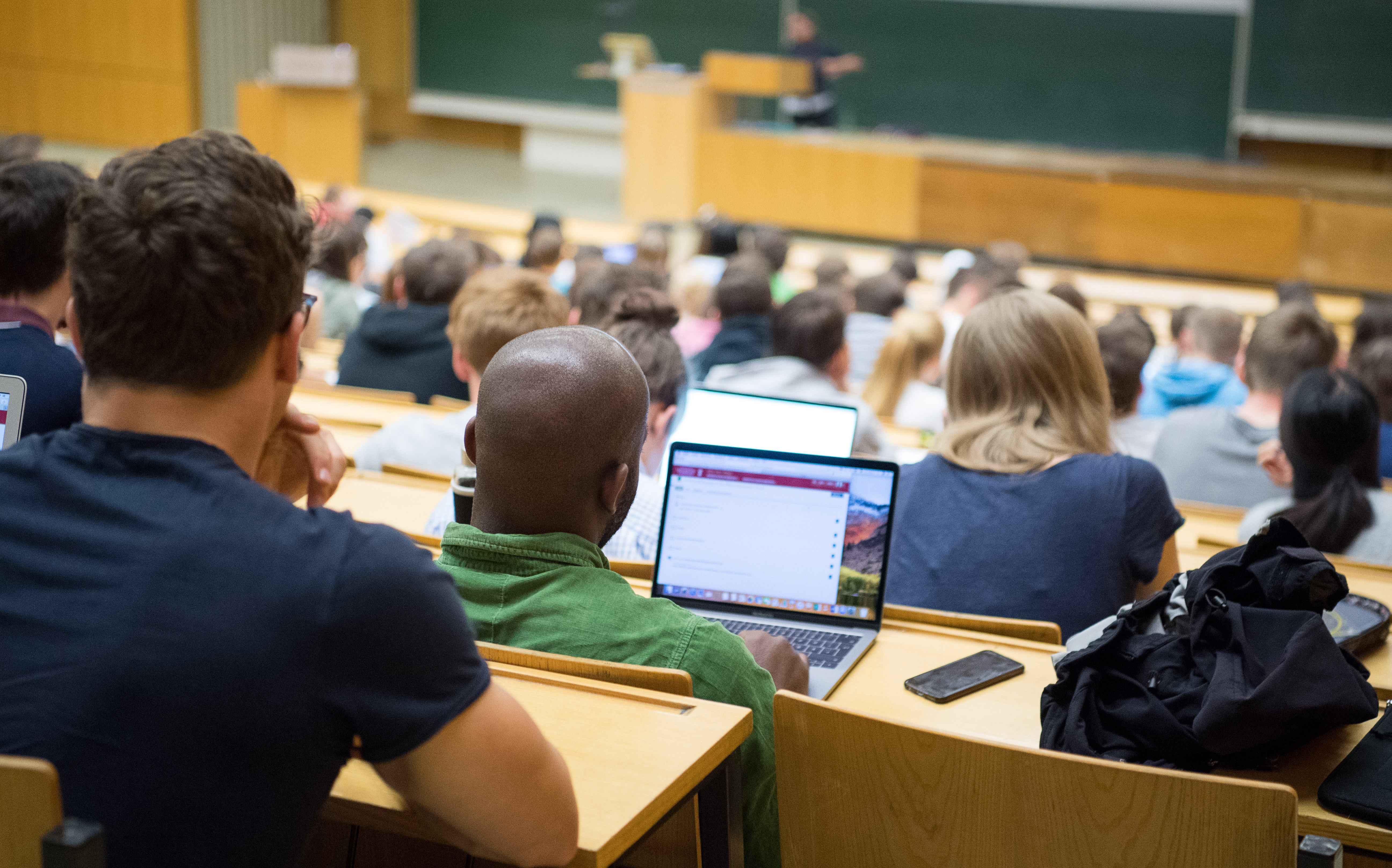Studierende sitzen mit Laptops in einer Vorlesung.