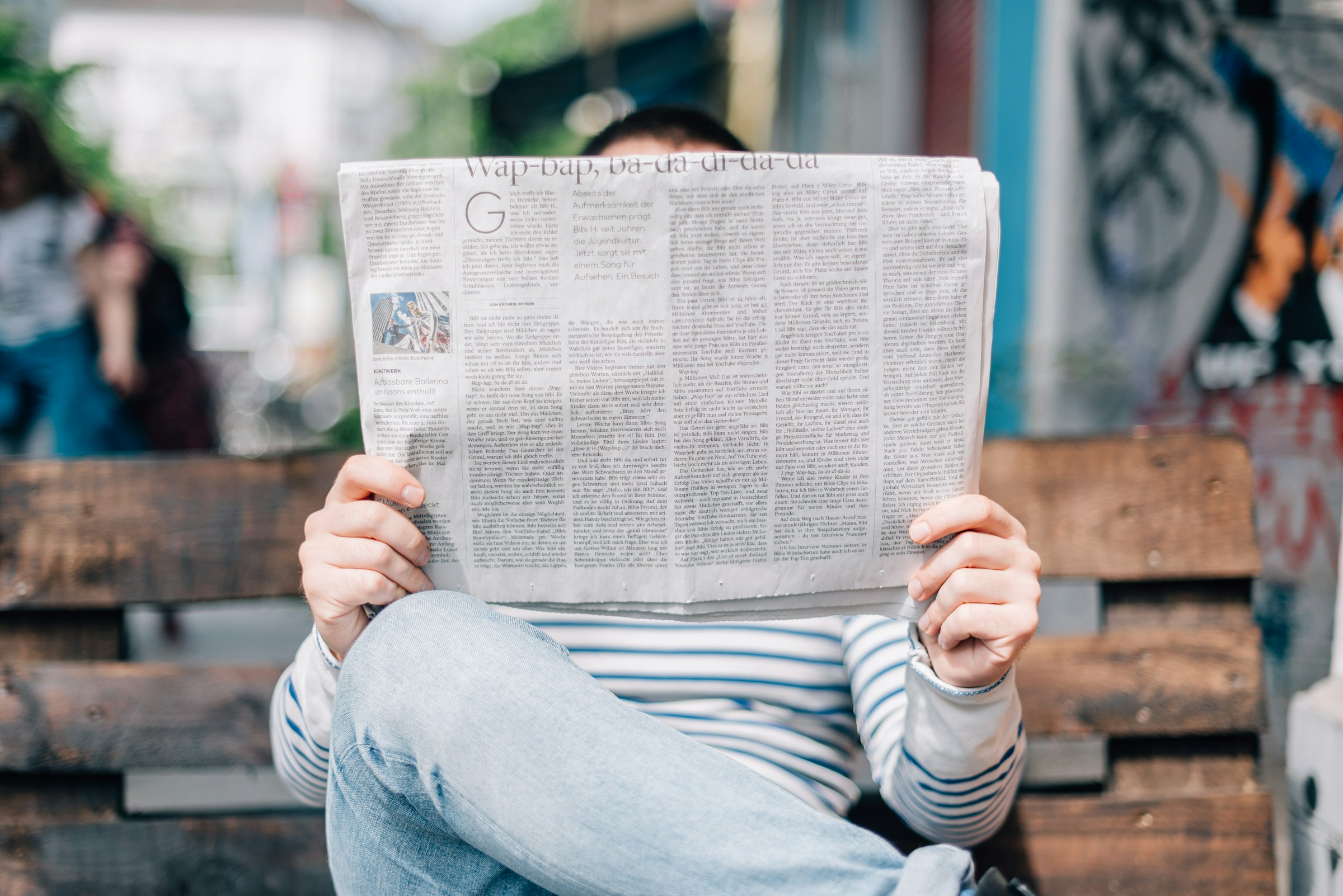 Persona leyendo un diario en una banca