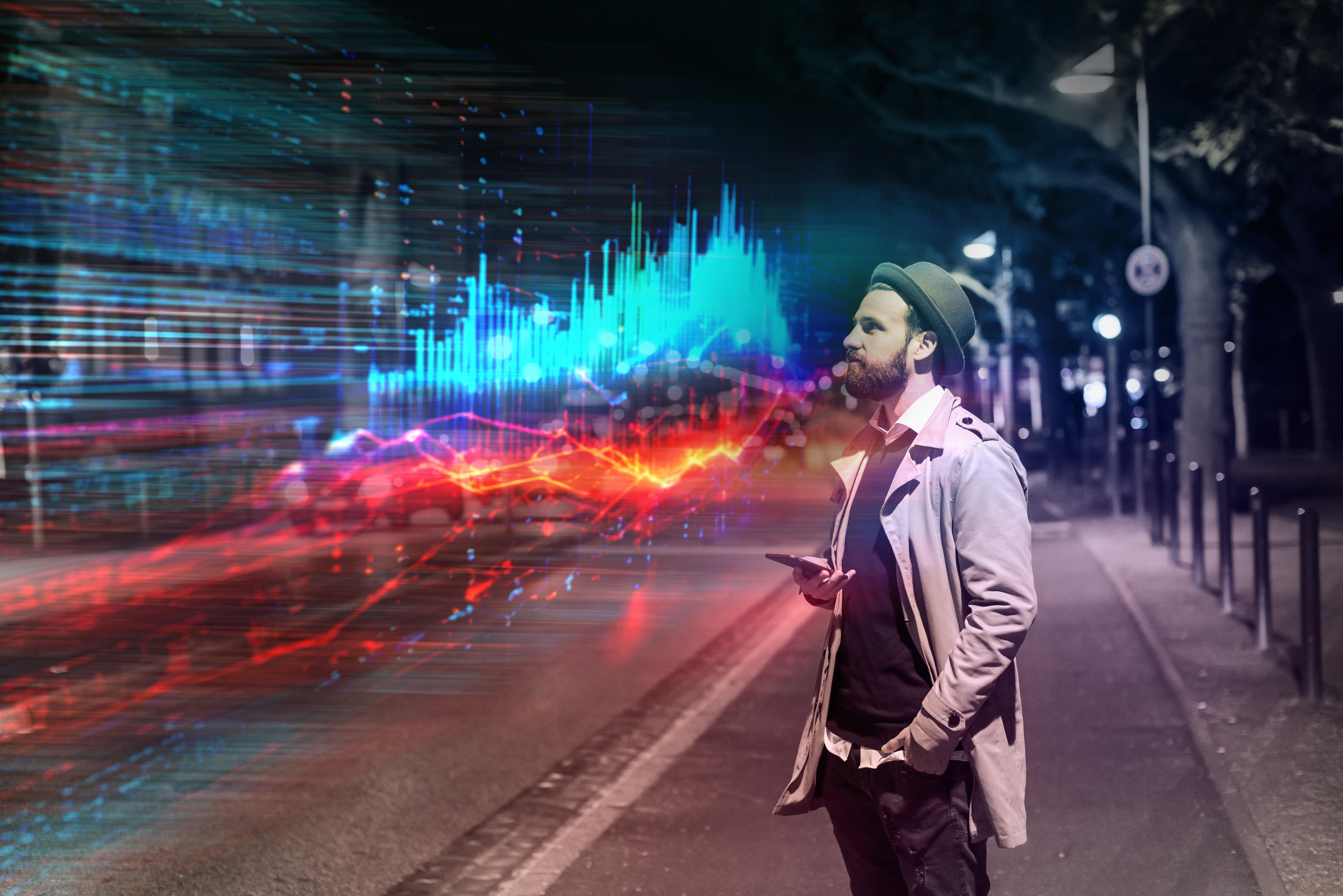 Junger Mann nutzt Smartphone mit Augmented-Reality-Datenvisualisierung auf einer Stadtstraße bei Nacht.