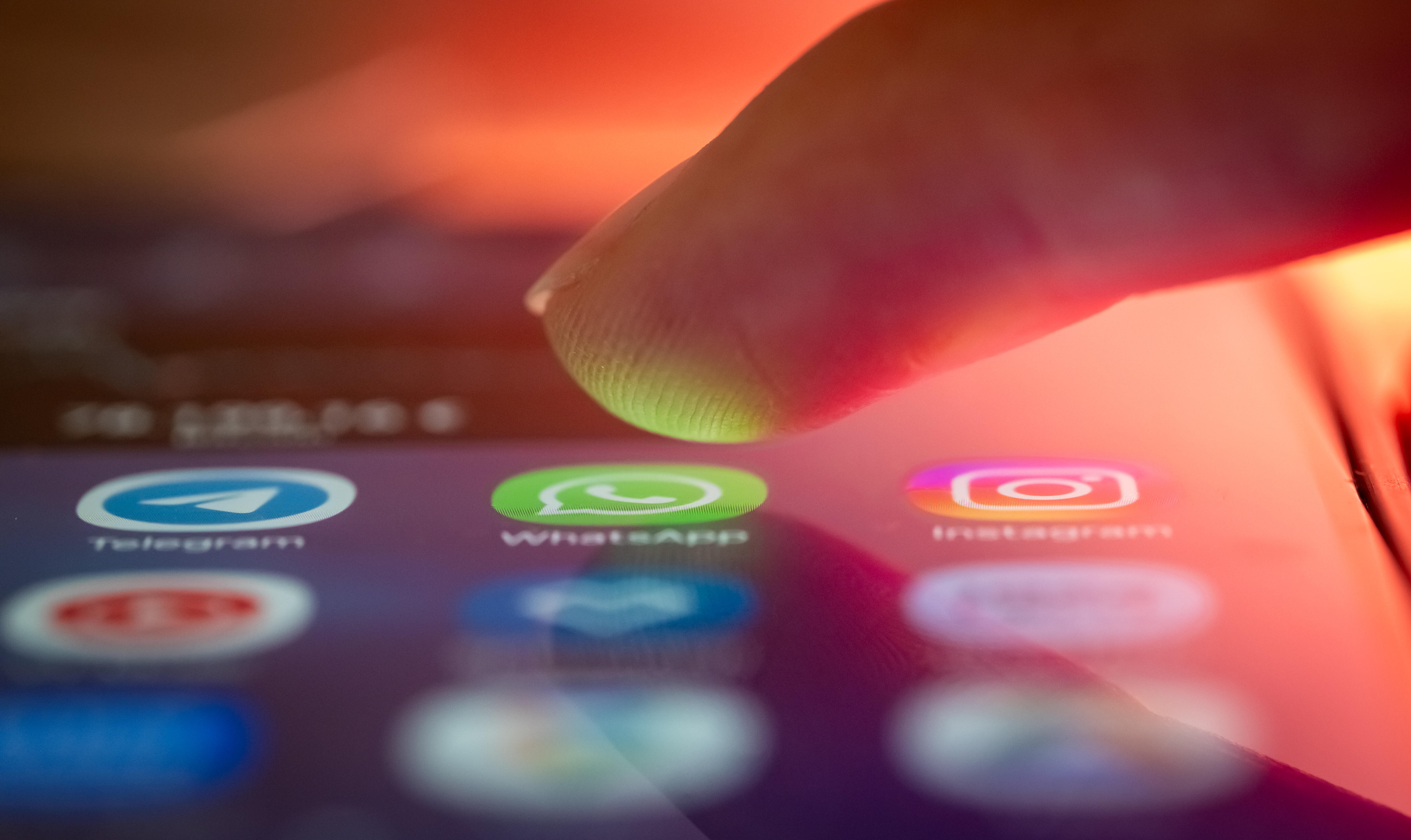 Finger über dem Smartphone, kurz vorm Öffnen einer Messenger-App