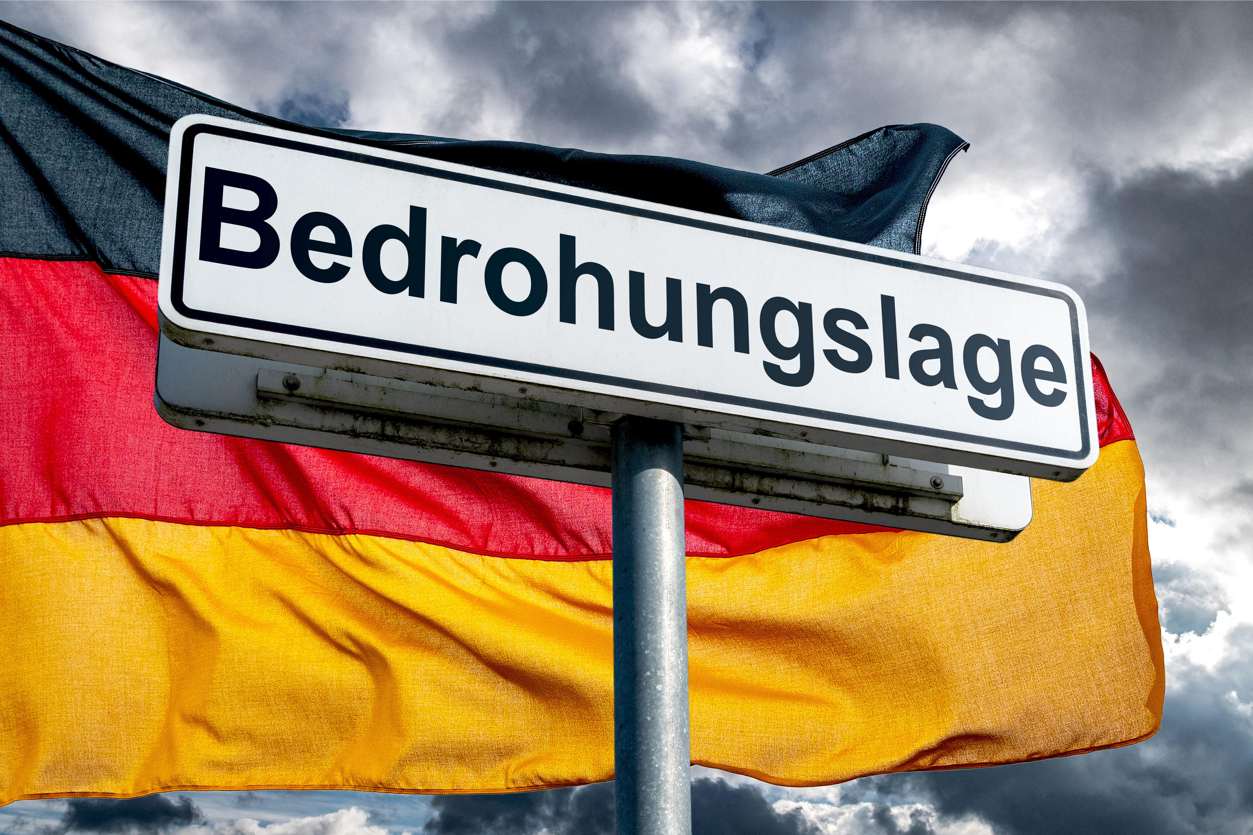 Warnschild ‚Bedrohungslage‘ vor der deutschen Flagge