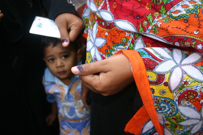 A women shows her voter ID card and inked finger after casting her vote in the parliamentary elections in Bangladesh
