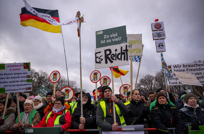 Teilnehmer der Demonstration der Landwirtinnen und Landwirte halten während der Kundgebung Schilder und Transparente hoch.