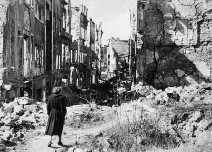 Eine Frau geht in einer Straße in Dresden an Häusern vorbei, von denen nach Bombenangriffen im Zweiten Weltkrieg nur noch Ruinen geblieben sind