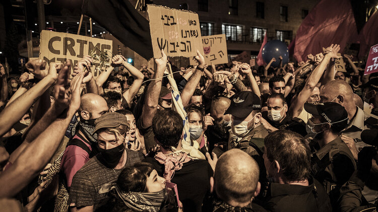Demonstranten stehen mit Plakaten mit der Aufschrift "Crime" bei Protesten gegen den israelischen Ministerpräsidenten in der Nähe seiner offiziellen Residenz