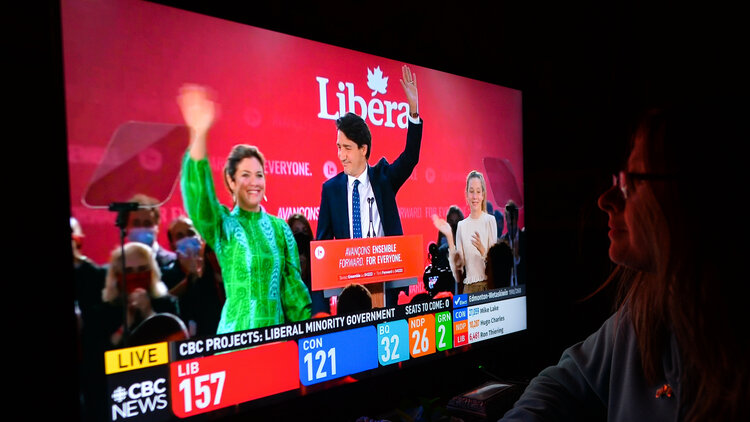 Eine Frau schaut eine Wahlsendun von CTS News auf dem Fernseher, die einen feiernden Justin Trudeau zeigt.