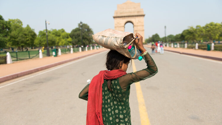 New Delhi, India, a girl carrying drinkable water bottles on her head during summer near India Gate
