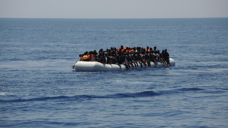 Migranten sitzen auf einem überladenen Schlauchboot im Mittelmeer. Auf solchen Booten versuchen Menschen, über das Mittelmeer nach Europa zu kommen.