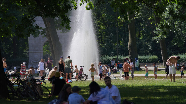 Zahlreiche Menschen suchen bei hochsommerlichen Temperaturen den kühlenden Springbrunnen im Treptower Park auf.
