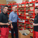 Asad Shirzad (l-r) aus dem Iran, Mario Ruckdäschel, Böroleiter der Wärmeversorgungsgesellschaft mbH und Mohamad Hamdo aus Syrien, Auszubildender, stehen nach einer Pressekonferenz zur Integration von Geflüchteten in den Arbeitsmarkt in Brandenburg am Unternehmensstandort der Wärmeversorgungsgesellschaft mbH in einem Materiallager.