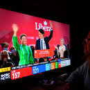 Eine Frau schaut eine Wahlsendun von CTS News auf dem Fernseher, die einen feiernden Justin Trudeau zeigt.