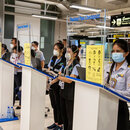 Mitarbeiterinnen warten auf Reisende am Suvarnabhumi International Airport in Bangkok