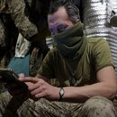 A Ukrainian serviceman looks at his phone 