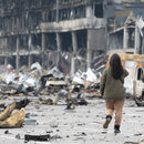  Eine junge Frau mit einem Mobiltelefon macht Fotos von einem zerstörten Einkaufszentrum in Retroville nach einem russischen Granatenangriff.