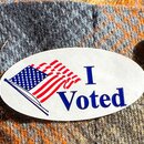 Ein "Ich habe gewählt" Sticker wird am Wahltag auf das Hemd einer Person gesteckt.