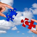 zwei Hände halten jeweils ein Puzzleteil von Europa und der Türkei 