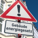 Warnschild "Gefahrstelle" (Zeichen 101) und ein Zusatzschild mit der Aufschrift "Gebäudeenergiegesetz".