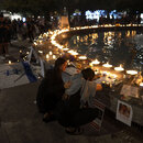 Menschen nehmen an einer Mahnwache bei Kerzenlicht teil