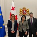 Die Präsidentin Salome Surabitschwili steht mit Vertretern der Stiftung vor georgischen und EU Flaggen