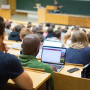 Studierende sitzen mit Laptops in einer Vorlesung.