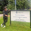 Rahman Imuda standing next to a signboard of IAF in Gummersbach.
