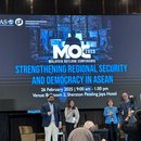 A picture from the stage of Malaysia Outlook Conference 2025. Four people (3 panelists and 1 moderator) are posing for a picture in front of the event banner.