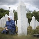 A woman mourns next to the grave of her relative, a victim of the Srebrenica genocide.