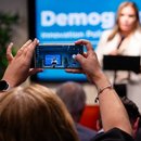 Women taking a picture of someone speaking