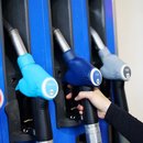 Eine Kundin an einer Tankstelle greift nach der Zapfpistole in einer Zapfsäule. 
