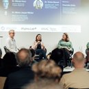 Nikolai Horn, Maren Jasper-Winter, Vivien Benert und Charlotte Zeller sitzen auf dem Podium; Maren Jasper-Winter spricht ins Mikrofon. Im Vordergrund ist das Publikum zu sehen.