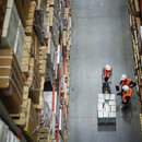 Blick von oben auf Arbeiter, die in einer Halle stehen. 