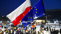 Demonstranten protestieren in Krakau mit der polnischen und der EU-Flagge gegen die geplante Mediensteuer