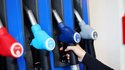 Eine Kundin an einer Tankstelle greift nach der Zapfpistole in einer Zapfsäule. 