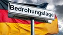 Warnschild ‚Bedrohungslage‘ vor der deutschen Flagge