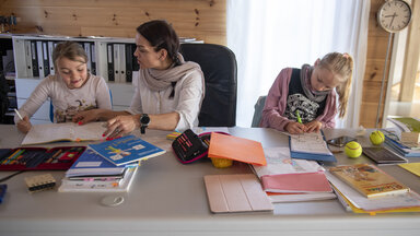 Mutter mit ihren Kindern beim Homeschooling