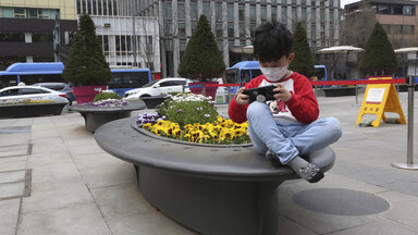 Ein kleiner Junge spielt mit seinem Smartphone in der Innenstadt von Seoul