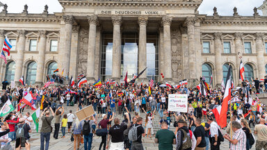 Demonstranten schwenken Reichskriegsflaggen vor dem Reichstag