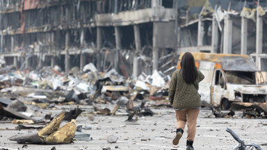  Eine junge Frau mit einem Mobiltelefon macht Fotos von einem zerstörten Einkaufszentrum in Retroville nach einem russischen Granatenangriff.
